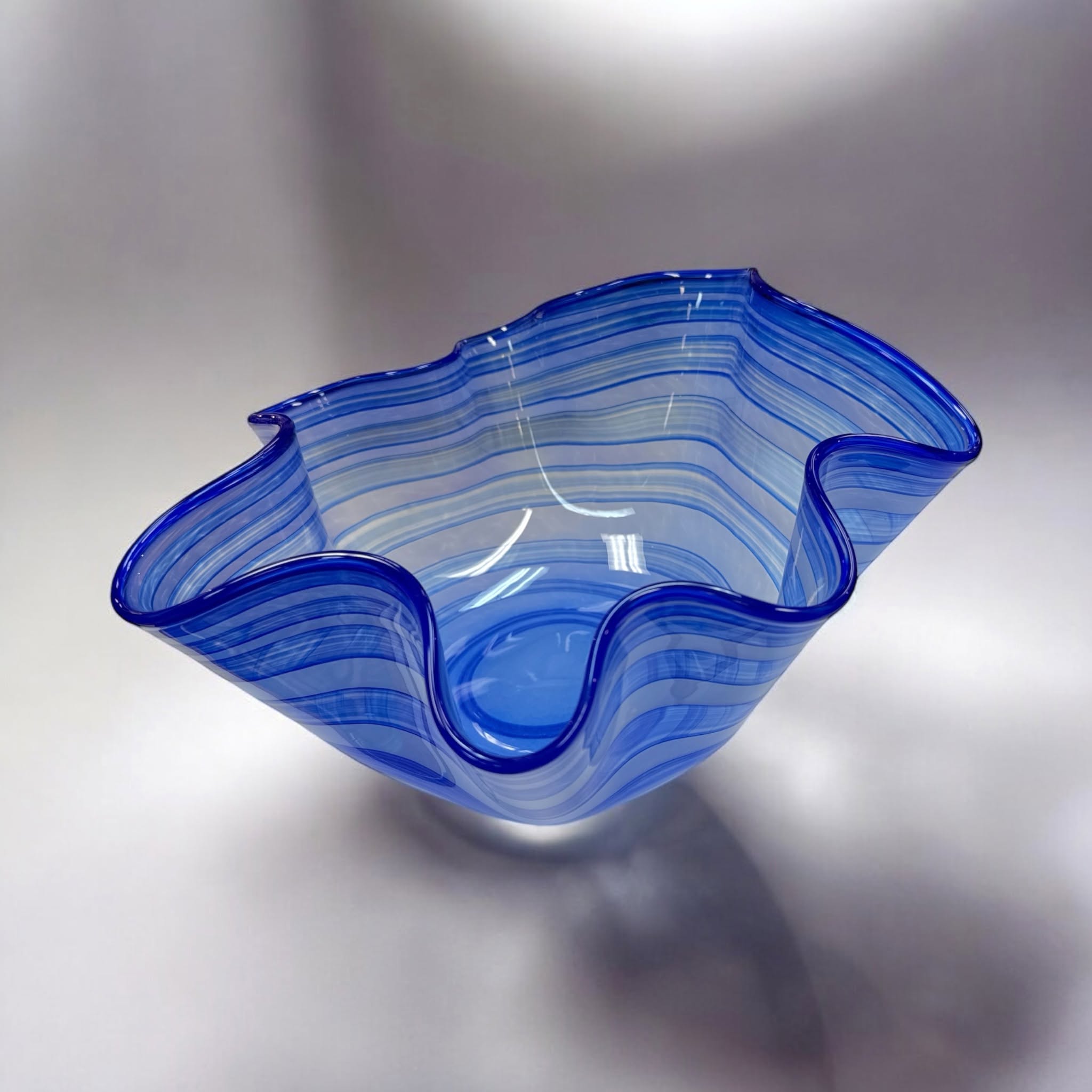 Blown glass bowl with a wavy rim and blue and white spiral bands, by Jordana Korsen