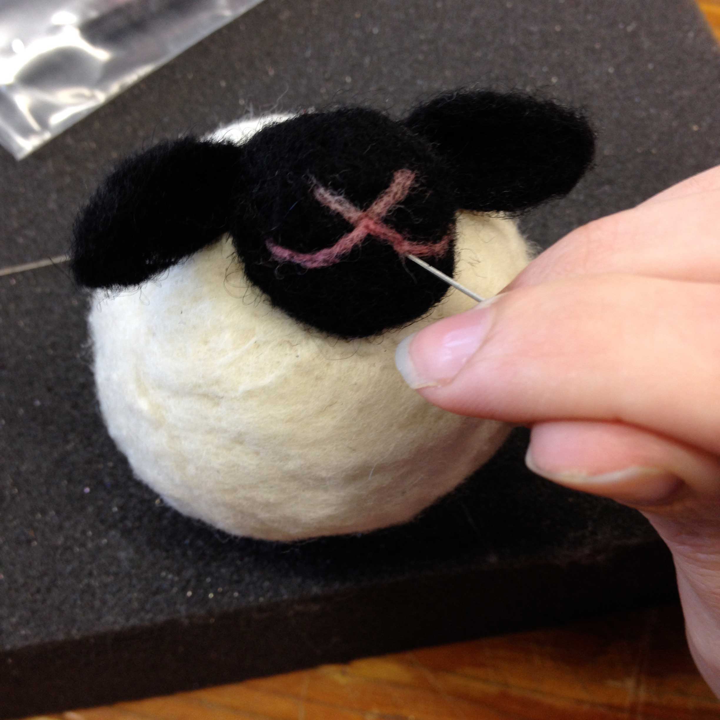 Hands shaping a needle felted lamb
