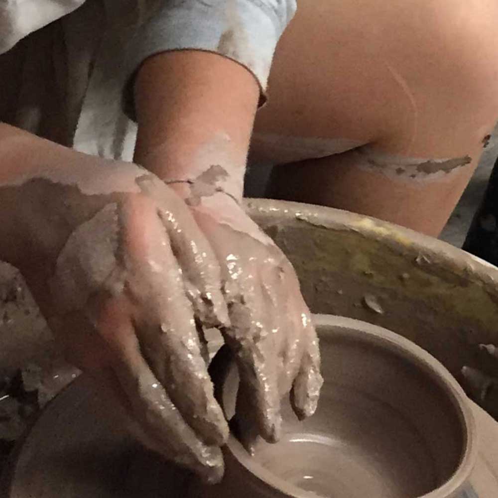 Students throwing pots at the wheels